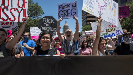 Protesters hold up signs as they march down Congress Ave at a pro-abortion protest