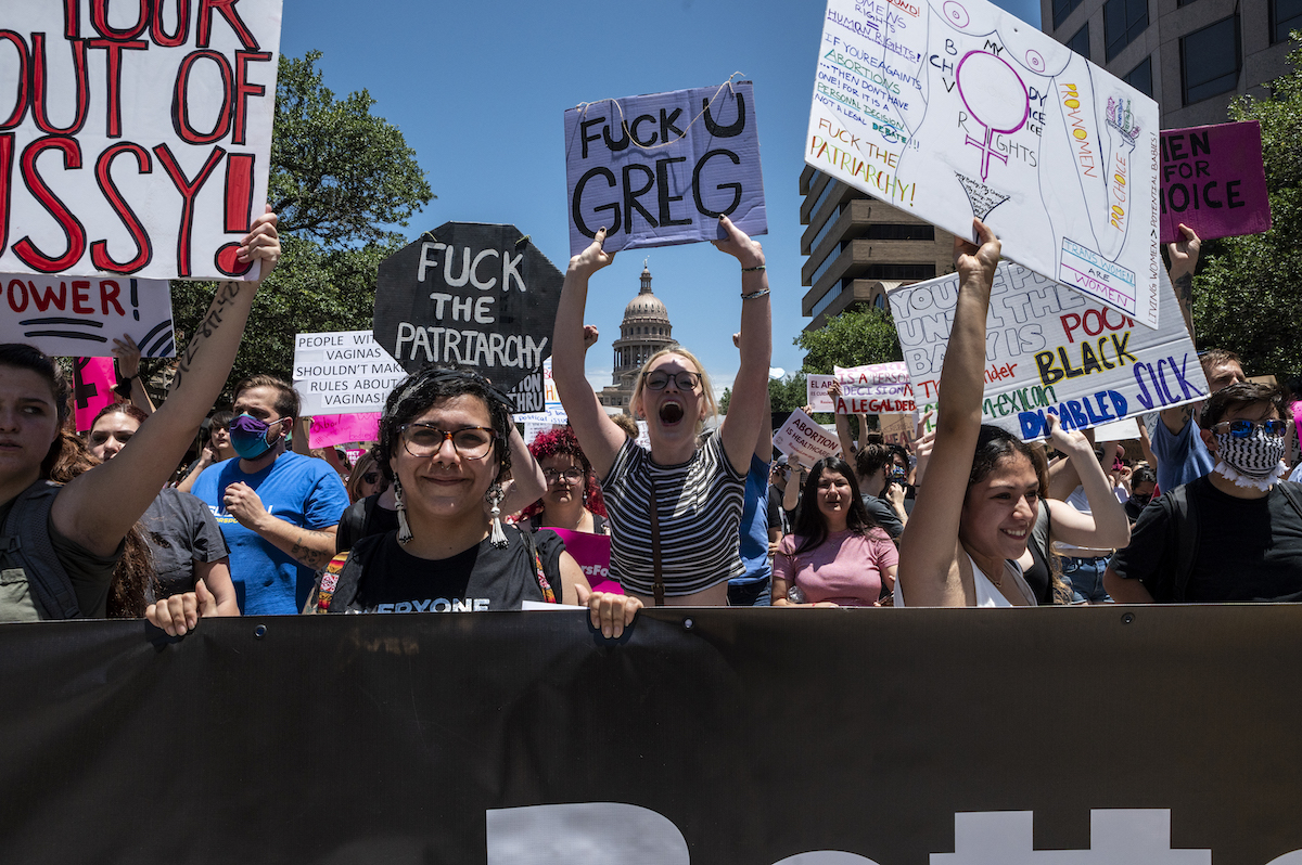 Protesters hold up signs as they march down Congress Ave at a pro-abortion protest