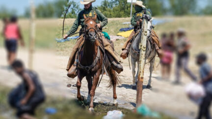 Slightly blurred image of federal agents on horses near the Rio Grande corralling Haitian refugees. (Image: John Moore/Getty Images.)