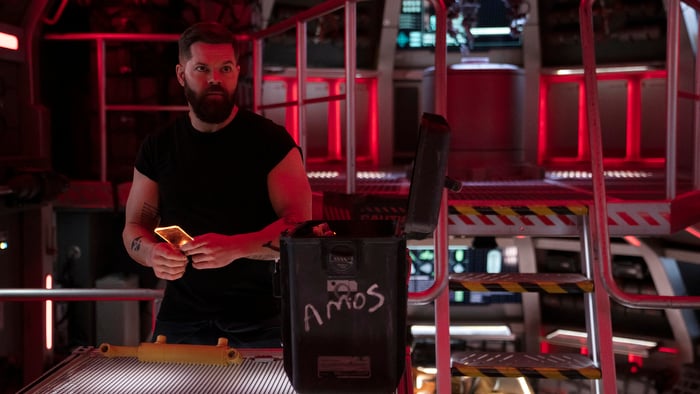 Wes Chatham stands beside a box labeled 'Amos' on the Rocinante ship as Amos in 'The Expanse' season six