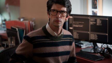 Ben Whishaw frowns in front of a computer as Q in 'No Time to Die'