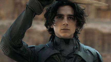 Paul (Timothee Chalamet) holds up a knife above his head in a scene from Dune.