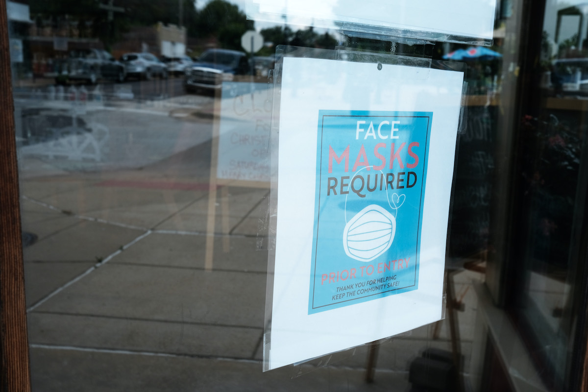 A sign in a store window reads "Face Masks Required"