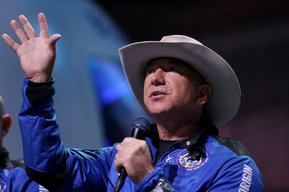 Jeff Bezos speaks while wearing a flight suit and a cowboy hat.