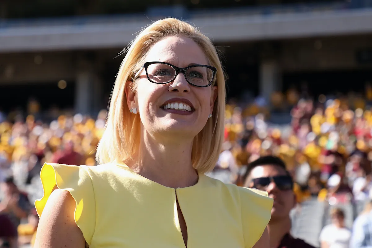 Kyrsten Sinema looks out at a crowd, smiling
