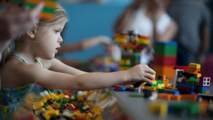 A young child plays with Lego building blocks