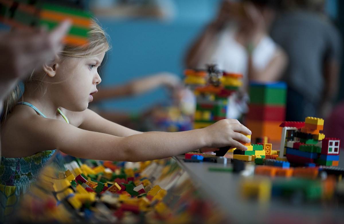 A young child plays with Lego building blocks