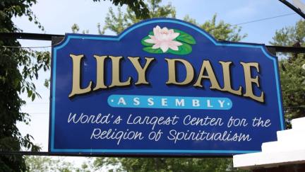 A blue sign with gold letters announcing the Lily Dale assembly, center for spiritualism