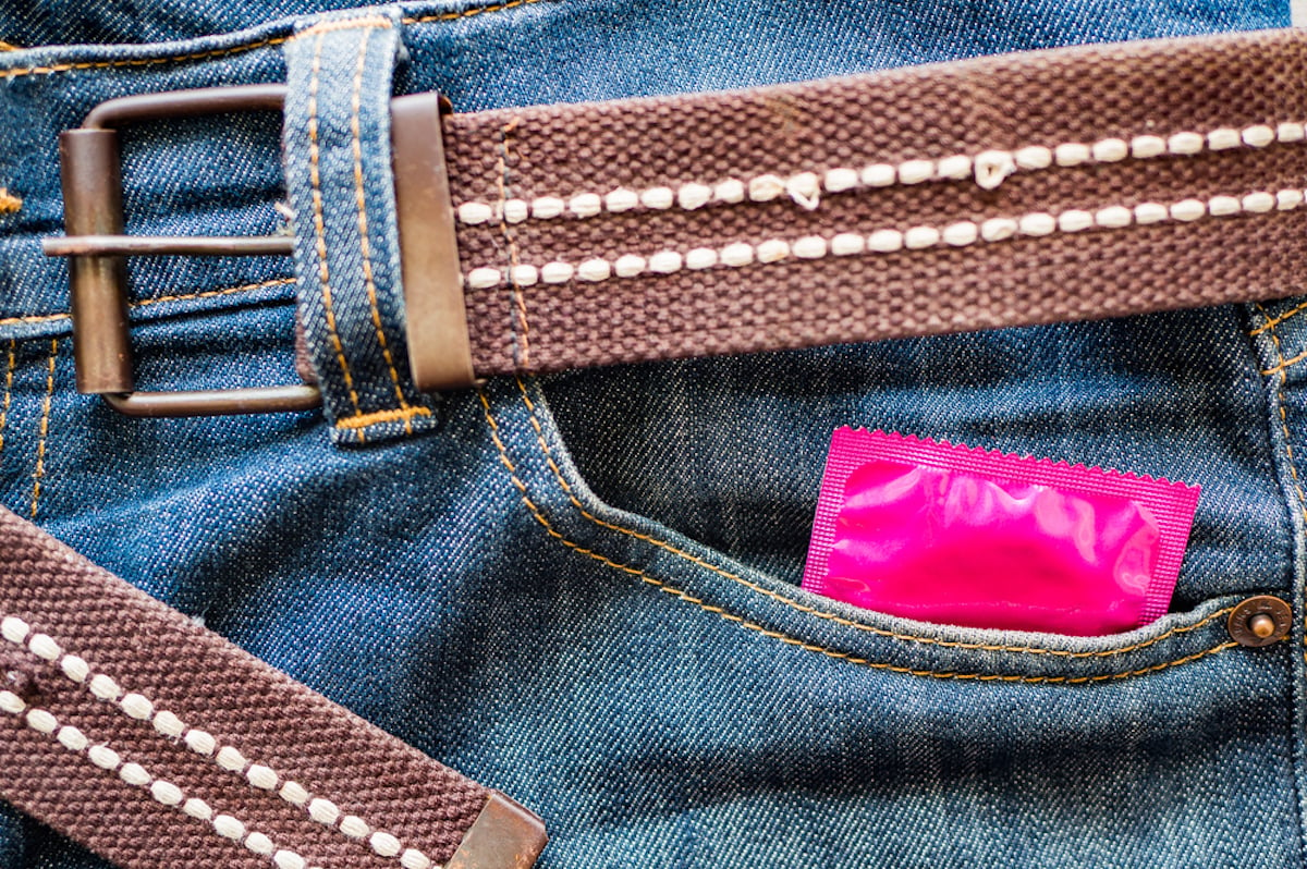 A pink condom wrapper peek out of a jeans pocket