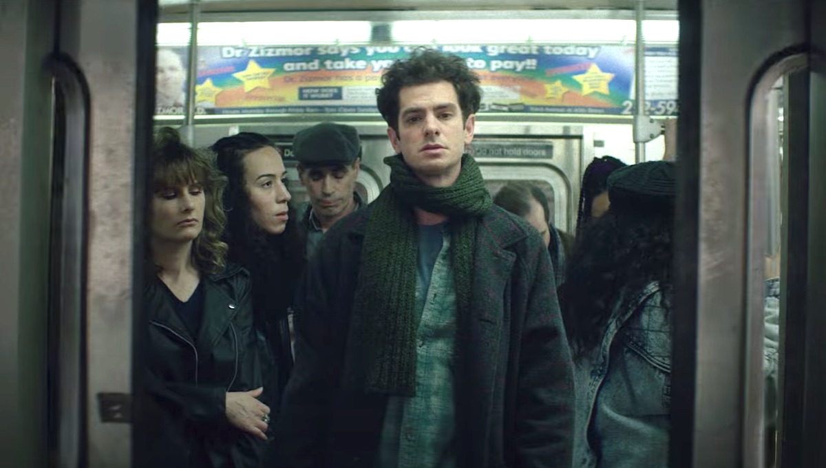 Andrew Garfield as Jonathan Larson stands in a packed '90s subway car in the movie 'Tick, Tick ... BOOM!'