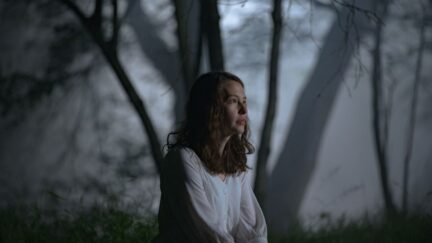 Cadi, played by Annes Elwy, sitting in the woods. (Image: IFC.)