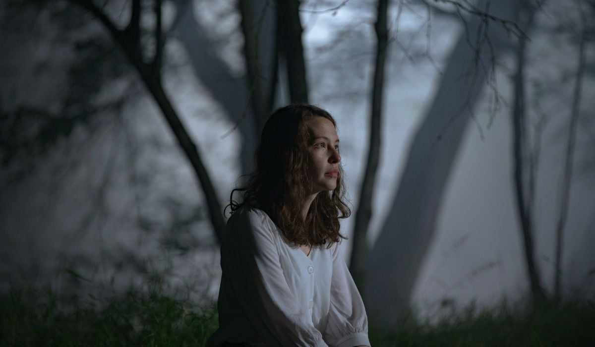 Cadi, played by Annes Elwy, sitting in the woods. (Image: IFC.)