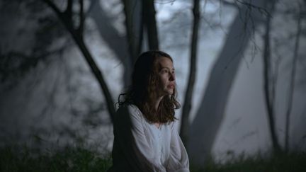 Cadi, played by Annes Elwy, sitting in the woods. (Image: IFC.)