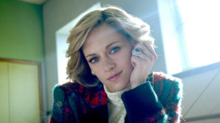 Kristen Stewart rests her cheek on her hand and looks into the camera as Diana in Spencer.