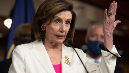 Speaker of the House Nancy Pelosi speaks and holds up her hand during a news conference
