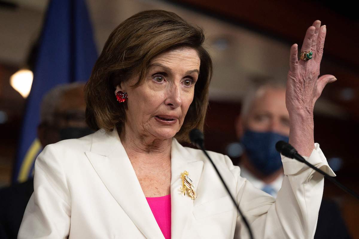 Speaker of the House Nancy Pelosi speaks and holds up her hand during a news conference