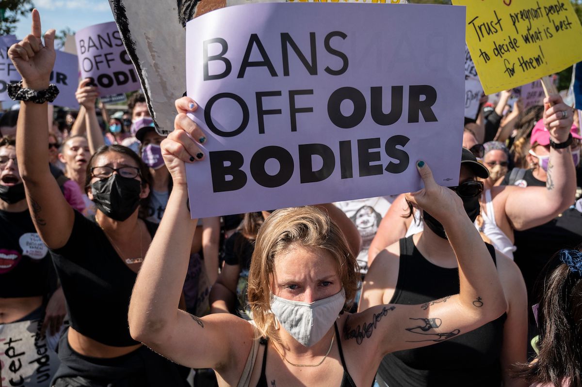 A protester at a pro-abortion rally hold a sign reading "BANS OFF OUR BODIES"