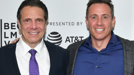 Chris and Andrew Cuomo stand together smiling on a red carpet