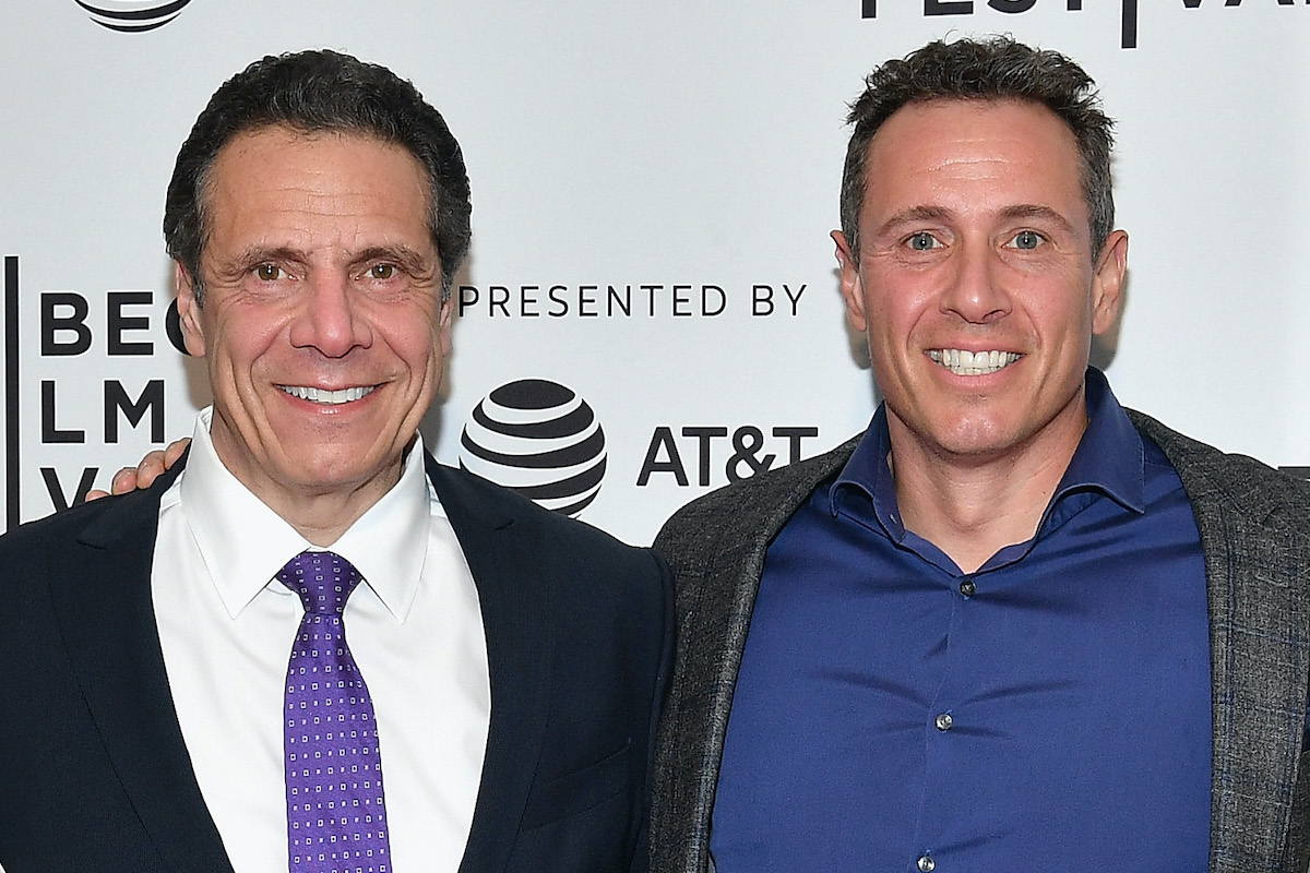 Chris and Andrew Cuomo stand together smiling on a red carpet