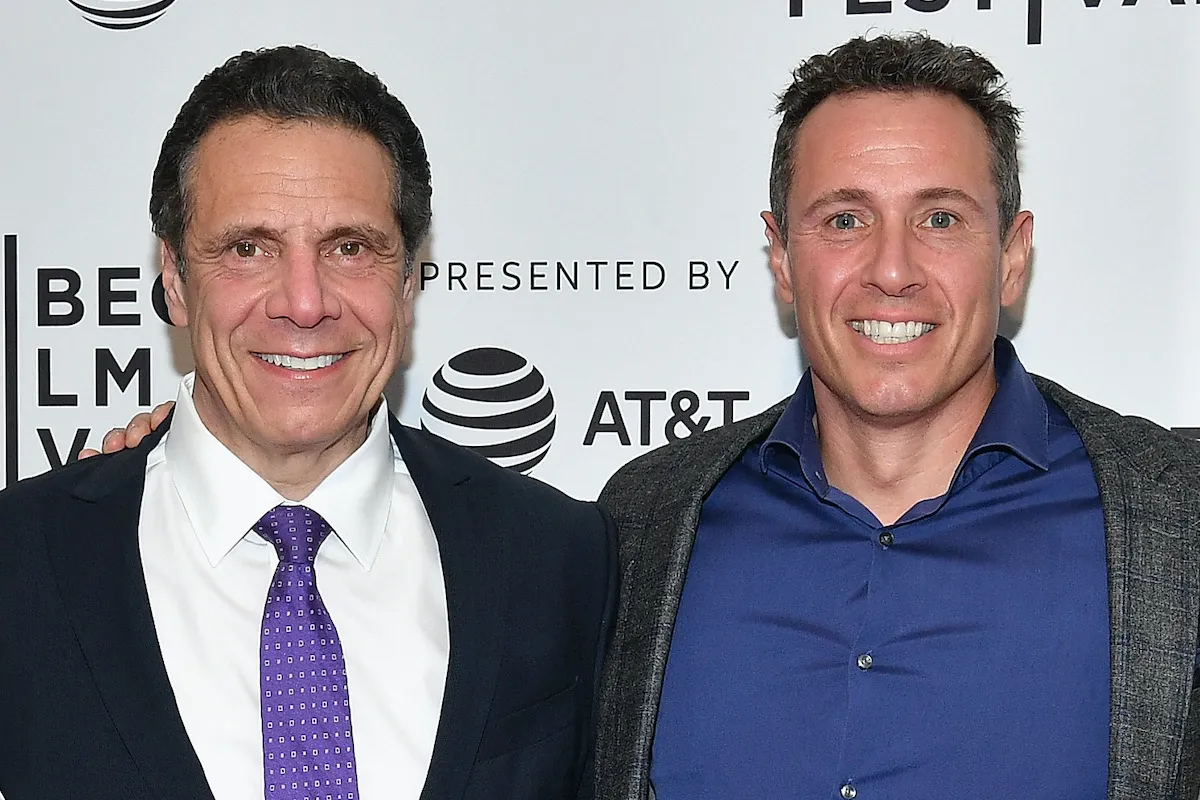 Chris and Andrew Cuomo stand together smiling on a red carpet