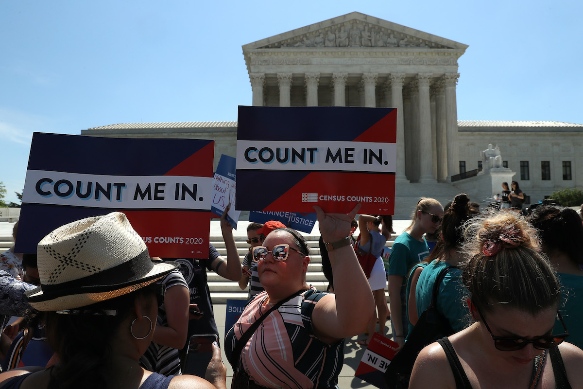 Protesters in front of the US Supreme Court building hold signs reading "Count Me In"