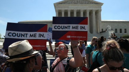 Protesters in front of the US Supreme Court building hold signs reading 