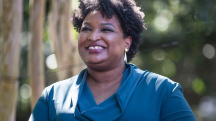 Stacey Abrams smiles against an outdoor background.