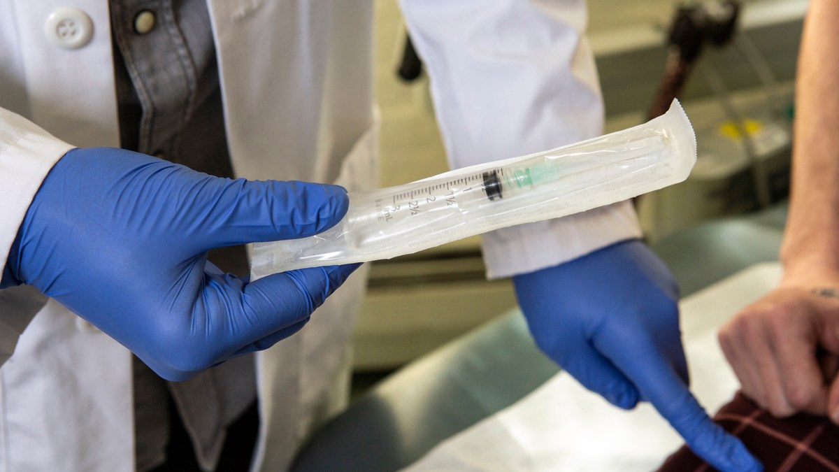 A doctor instructs a trans person how to inject testosterone.