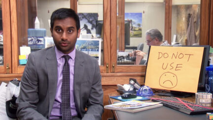 Tom Haverford sitting in front of a computer that says 