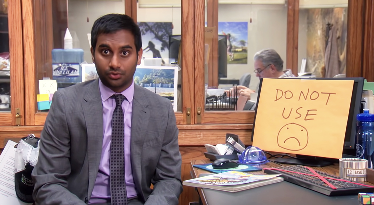 Tom Haverford sitting in front of a computer that says "do not use"