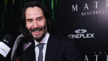 Keanu Reeves smiles while talking to media on the red carpet for The Matrix Resurrections
