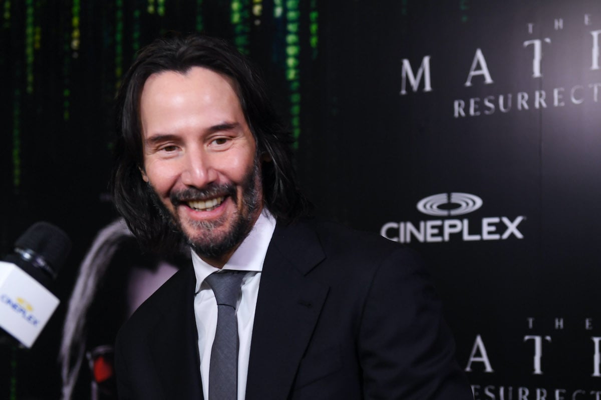 Keanu Reeves smiles while talking to media on the red carpet for The Matrix Resurrections