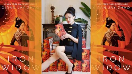 Xiran on their throne flanked by copies of their debut book. (Image: Xiran Jay Zhao and Penguin Teen.)