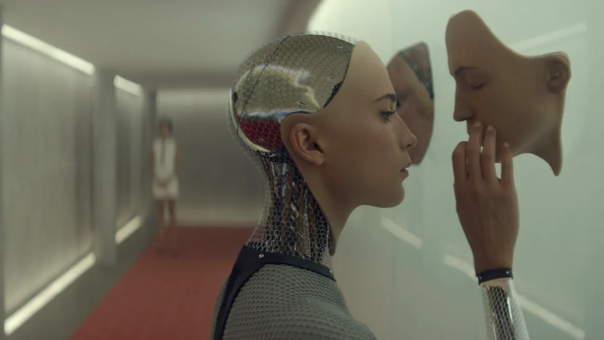 Ava tests the limits of her self-awareness by examining another face in Ex Machina.