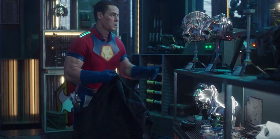 Peacemaker gathering up superpowered helmets into a duffel bag, with his shield in a crate behind him.