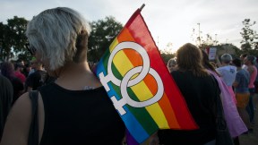A person holds a rainbow flag with two female symbols on it