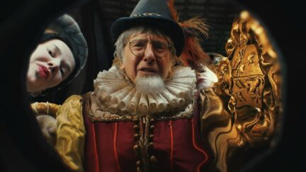 Larry David dressed in a Renaissance costume, peering into the camera from above