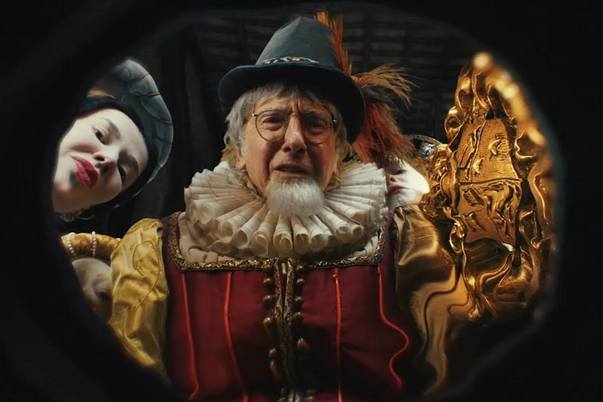 Larry David dressed in a Renaissance costume, peering into the camera from above