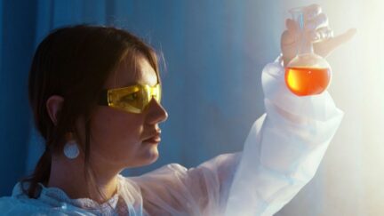 Scientist looking at a beaker. (Image: Artem Podrez from Pexels.)