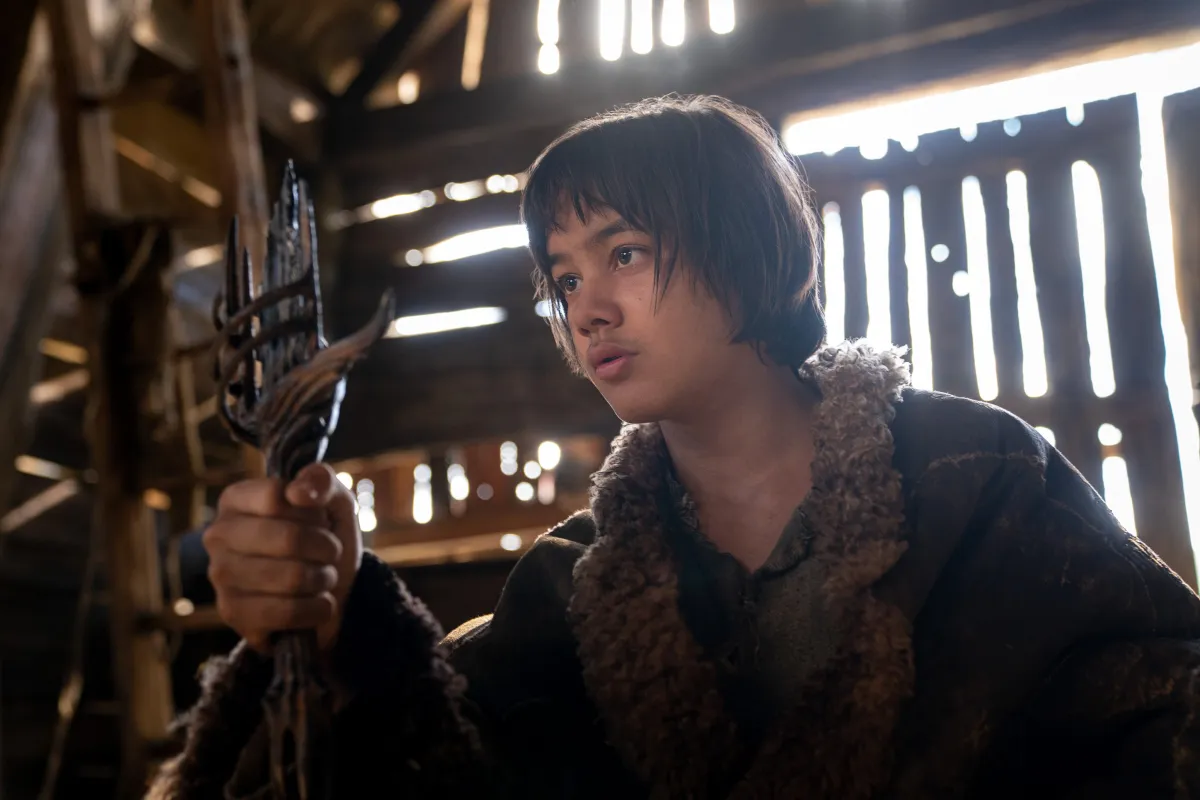 A young boy named Theo holds up the hilt of a broken sword