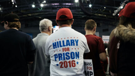 A Trump supporter sits in a crowd wearing a t-shirt reading 