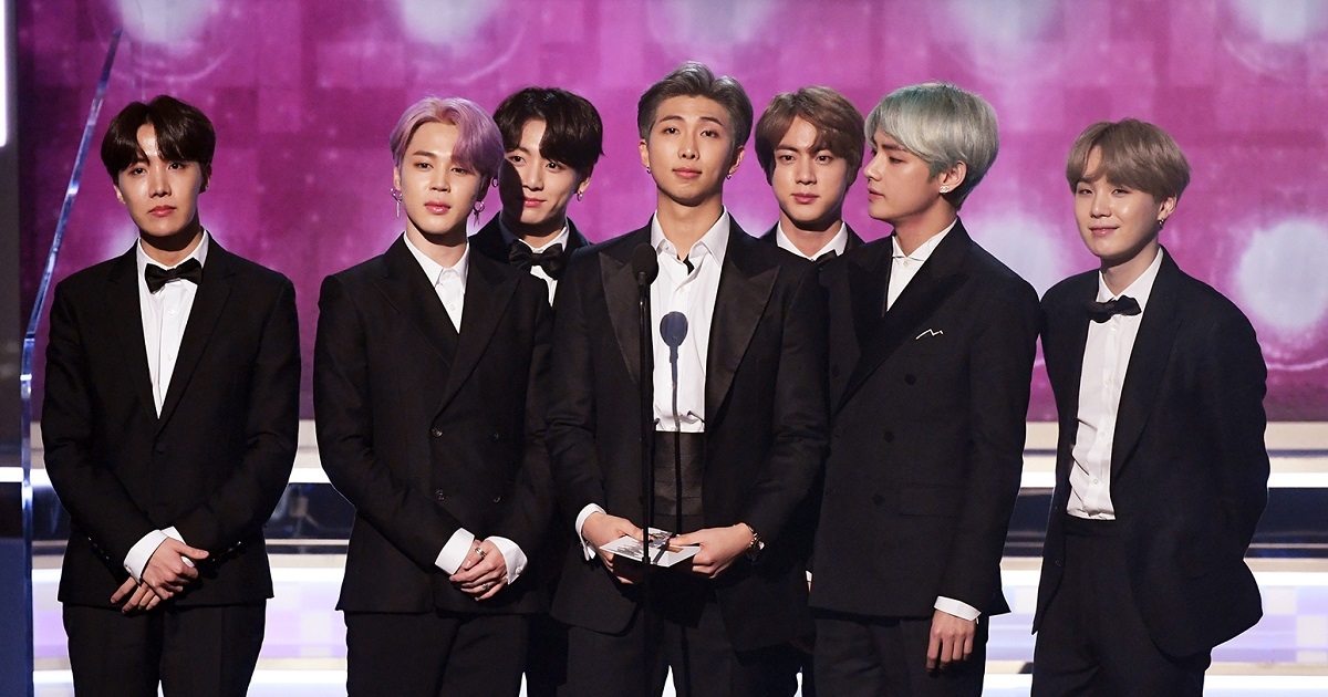 A picture of the seven members of BTS (left to right: J-hope, Jimin, Jungkook, RM, Jin, V and SUGA) presenting an award at the 2019 Grammy Award Ceremony