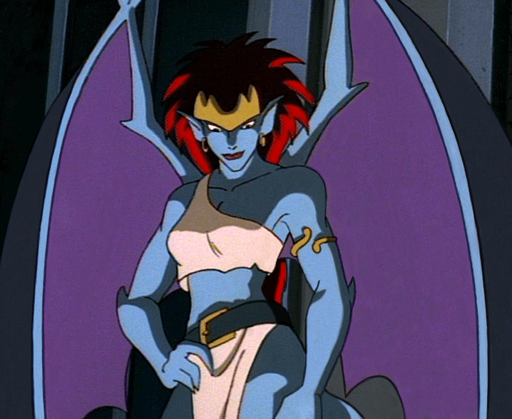 Demona, a gargoyle wearing a crown and a gold arm band, looks down and smiles.
