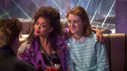 Gugu Mbatha-Raw puts her arm around Mackenzie Davis, both dressed in 80s clothing in Black Mirror (2011)