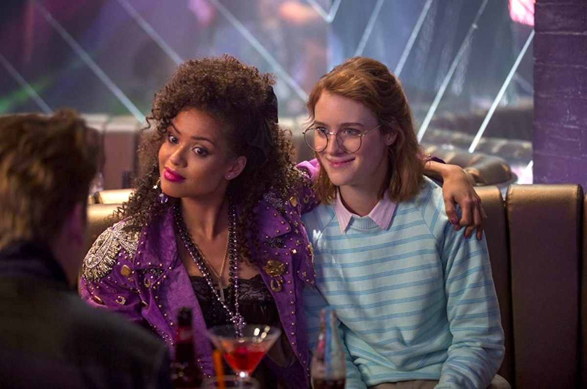 Gugu Mbatha-Raw puts her arm around Mackenzie Davis, both dressed in 80s clothing in Black Mirror (2011)