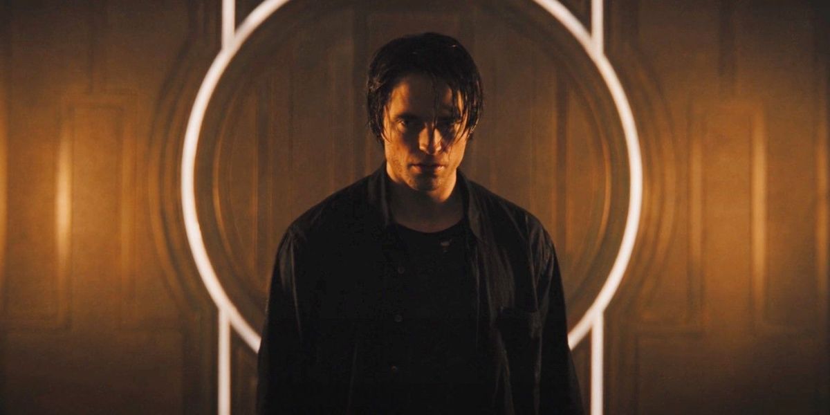 Robert Pattinson as Bruce Wayne standing in front of a light