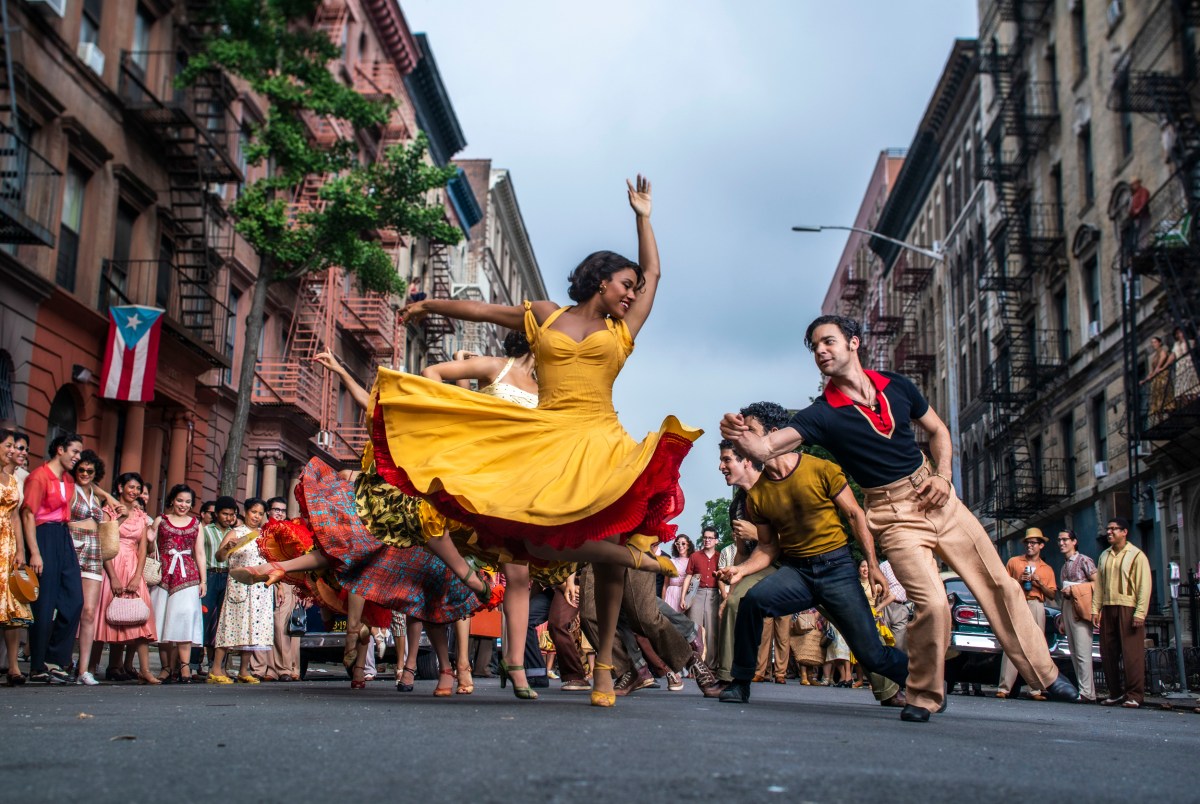 West Side Story Still, Ariana DeBose in a Yellow Dress leaps into the air.