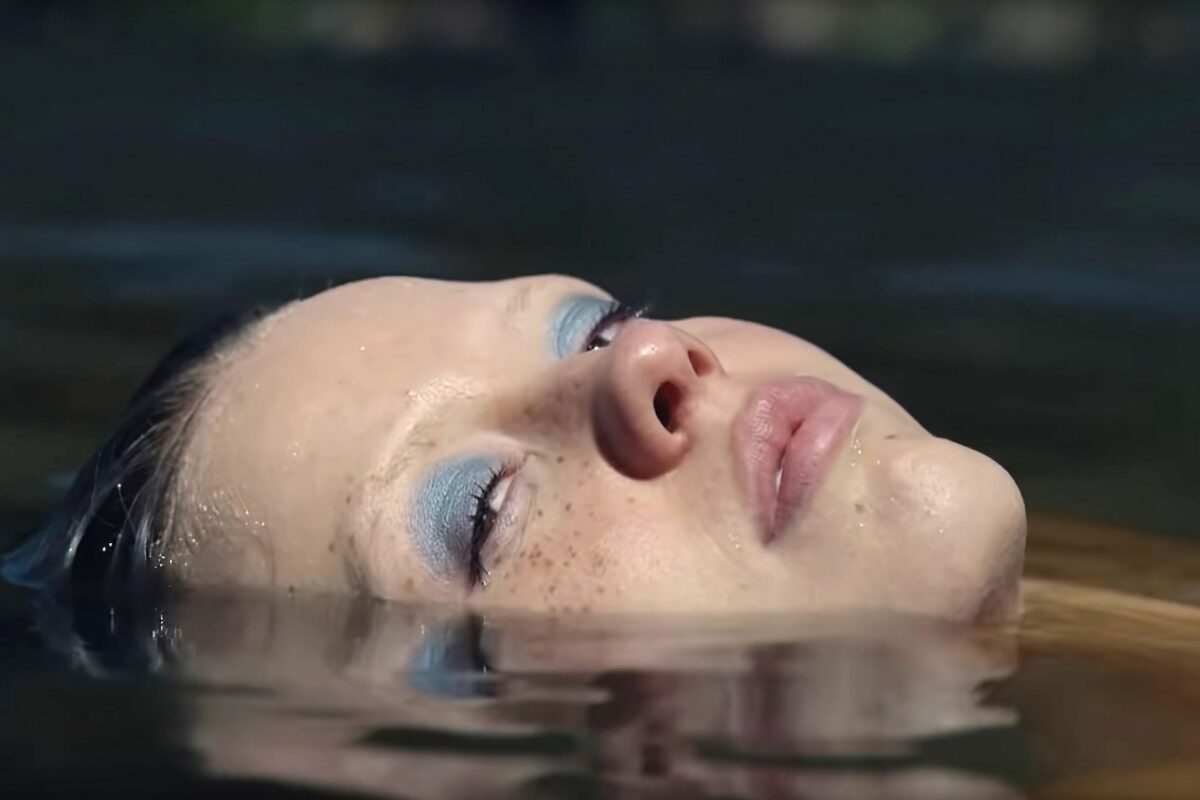 a close up of Mia Goth's face in a pool of water