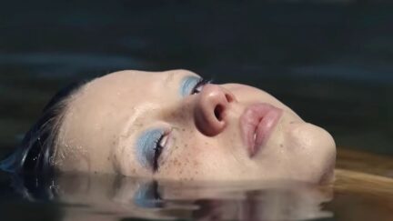 a close up of Mia Goth's face in a pool of water