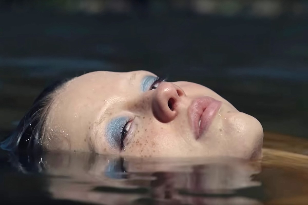 a close up of Mia Goth's face in a pool of water